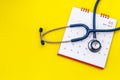 Blue stethoscope and white calendar on yellow background. Schedule to check heart or health check up concept Royalty Free Stock Photo
