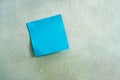 Blue sticky note on a plastered gray wall