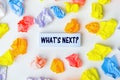 Blue sticky note with the text What`s Next and some colorful crumpled paper balls around it on white background, text concept. Royalty Free Stock Photo