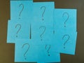 Blue Sticky Notes with Question Marks - Arrangement of blue sticky notes, each with a question mark, against a dark background. Royalty Free Stock Photo