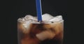 Blue straw in cola with ice cubes in glass over black background Royalty Free Stock Photo