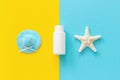 Blue straw hat, starfish and white tube, bottle of sunscreen on yellow and blue paper background. Mock up Template for lettering,