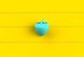 Blue strawberry on yellow wooden board