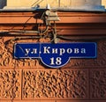 Blue street sign and house numbers on a building wall.