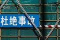 a blue street sign sitting under a metal fence on a green wall