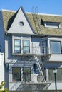 Blue stucco house with light brown roof tiles and metal fire escape saftey ladder on front yard of home in the downtown Royalty Free Stock Photo