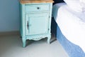 Blue stylish nightstand. Stylish nightstand next to elegant bed in bedroom.