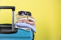 Blue suitcase with sun glasses, summer clothes, shoes and wicker bag on yellow background Royalty Free Stock Photo