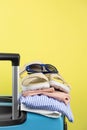 Blue suitcase with sun glasses, summer clothes, shoes and wicker bag on yellow background Royalty Free Stock Photo