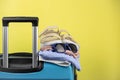 Blue suitcase with sun glasses, summer clothes, shoes and wicker bag on yellow background Royalty Free Stock Photo