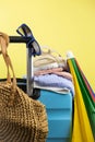 Blue suitcase with sun glasses, summer clothes, shoes and wicker bag on yellow background Royalty Free Stock Photo