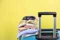 Blue suitcase with sun glasses, summer clothes, shoes and wicker bag on yellow background Royalty Free Stock Photo
