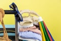 Blue suitcase with sun glasses, summer clothes, shoes and wicker bag on yellow background Royalty Free Stock Photo