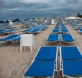 Blue sunbeds in neat rows in South Beach, Miami; stormy day, grey clouds