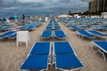 Blue sunbeds in neat rows in South Beach, Miami; stormy day, grey clouds