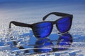 Blue sunglasses with black frames on water reflection with selective focus Royalty Free Stock Photo