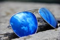 Blue sunglasses on the stone withe reflection from sun and clouds Royalty Free Stock Photo