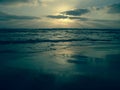 Blue sunset under a cloudy sky on a sandy beach with reflections on the wet sand.