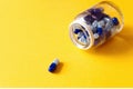 blue supplement pills spilled out of jar on yellow background Royalty Free Stock Photo