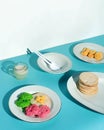 A blue surface holds white plates with Indonesian snacks. One has a stack of Kue Lumpur cakes, another has jackfruit pieces, and a Royalty Free Stock Photo