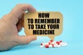 On a blue surface are pills in a persons hand, a sign with the inscription - How to remember to take your medicine Royalty Free Stock Photo