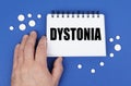 On the blue surface of the tablet, a hand and a notepad with the inscription - DYSTONIA Royalty Free Stock Photo
