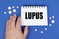 On the blue surface of the tablet, a hand and a notepad with the inscription - LUPUS Royalty Free Stock Photo