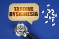 On the blue surface of the tablet, a stethoscope and a cardboard sign with the inscription - Tardive dyskinesia