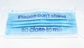 Blue surgical mask with the indication to maintain social distancing and not to stay so close. Covid-19 pandemic and social