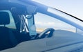 Blue surgical mask and a stethoscope hanging from the rearview mirror of a medical car with the background slightly out of focus