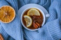 Blue sweater and cup of hot tea with lemon cinnamon sticks and anise star. Dry slices of citrus orange and cones. Hot Royalty Free Stock Photo