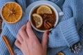 Blue sweater and cup of hot tea with lemon cinnamon sticks and anise star. Dry slices of citrus orange and cones. Hot Royalty Free Stock Photo