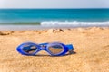 Blue swimming goggles lying at beach with sea Royalty Free Stock Photo