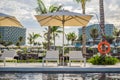 Blue swimming pool with beach lounger with parasol, sun deck on sea view for summer vacation Royalty Free Stock Photo