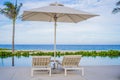 Blue swimming pool with beach lounger with parasol, sun deck on sea view for summer vacation Royalty Free Stock Photo