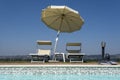 Blue swimming pool with beach lounger with parasol, sun deck on sea view for summer vacation Royalty Free Stock Photo