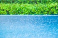 Blue swimming pool in the rain, blurred green garden backgrounds. Exterior tropical pool. Selective focus Royalty Free Stock Photo