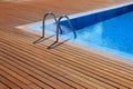 Blue swimming pool with teak wood flooring Royalty Free Stock Photo