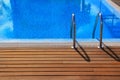 Blue swimming pool with teak wood flooring