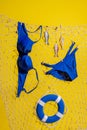 A blue swimsuit and wooden fish with a lifebuoy hang on a fishing net on a yellow background Royalty Free Stock Photo