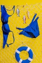 A blue swimsuit and wooden fish with a lifebuoy hang on a fishing net on a yellow background Royalty Free Stock Photo