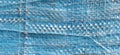 Blue synthetic burlap, close-up. Polyethylene material. Interlacing of polyethylene fibers and threads. Folds and bruises. Packing