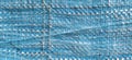 Blue synthetic burlap, close-up. Polyethylene material. Interlacing of polyethylene fibers and threads. Folds and bruises. Packing