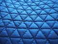 Blue synthetic quilted raincoat fabric close-up. Machine stitches are sewn in several directions to create an effect of Royalty Free Stock Photo