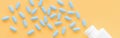 Blue tablets pills falling out of container on yellow background Royalty Free Stock Photo