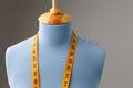 Blue tailor dummy with measuring tape alongside the wall. Royalty Free Stock Photo
