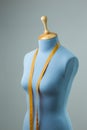 Blue tailor dummy with measuring tape alongside the wall. Royalty Free Stock Photo