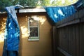 Blue tarp blown off damaged roof from storm bathroom window