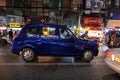 Blue taxi driving on the busy roads of the Chinatown in Bangkok during the nighttime