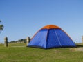 Blue tent with orange peak erected beside beach